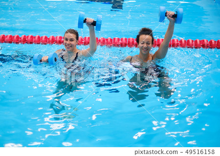 Multiracial couple attending water aerobics class in a swimming pool 49516158