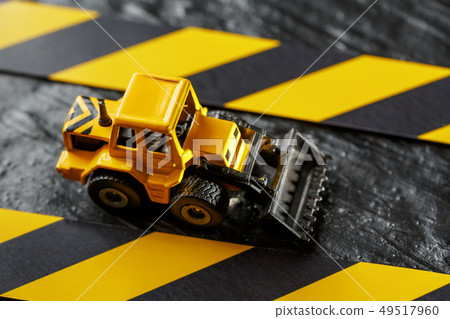 Yellow toy bulldozer on a black background Yellow toy bulldozer on a black background 49517960
