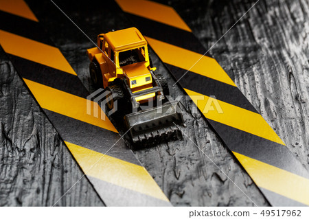 Yellow toy bulldozer on a black background 49517962