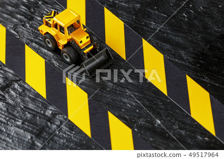 Yellow toy bulldozer on a black background 49517964