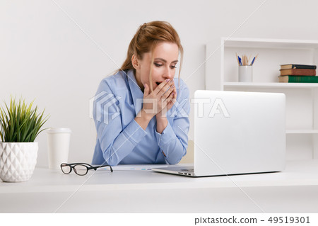 Exited woman surprised by something watching her laptop at office. 49519301