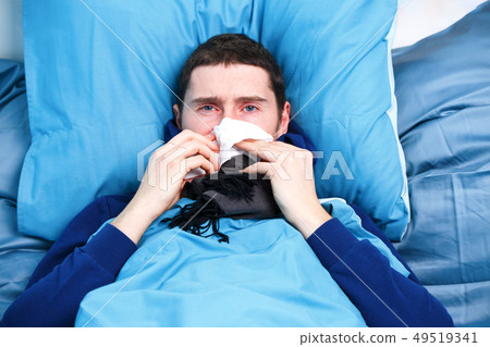 Photo of sick man with handkerchief sitting in bed Photo of sick man with handkerchief sitting in bed 49519341