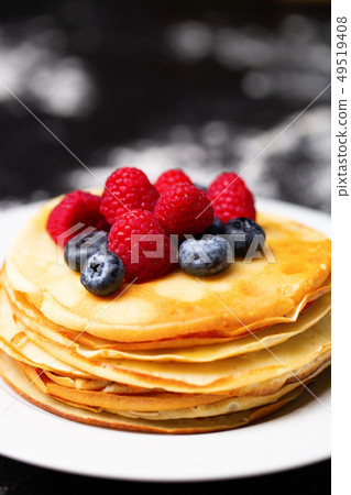 Closeup image of plate of pancakes, blueberries, raspberries and powdered sugar. Closeup image of plate of pancakes, blueberries, raspberries and powdered sugar. 49519408