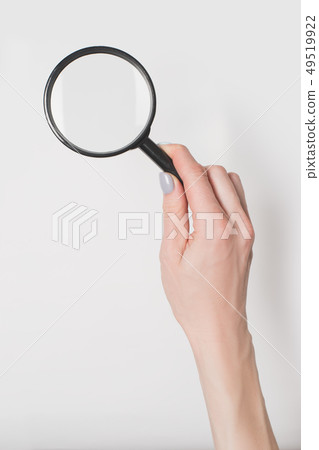 Female hand holding magnifier isolate on light 49519922