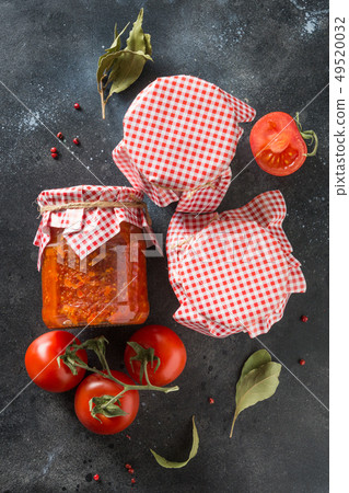 Homemade adjika with tomatoes in jar on dark Homemade adjika with tomatoes in jar on dark 49520032