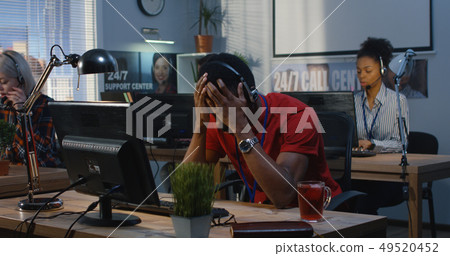 Tired man working at a support center 49520452