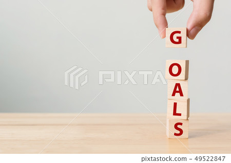 Hand putting wood cube with word GOALS 49522847