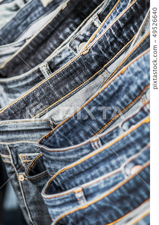 many different models of jeans hanging on hangers  49526640