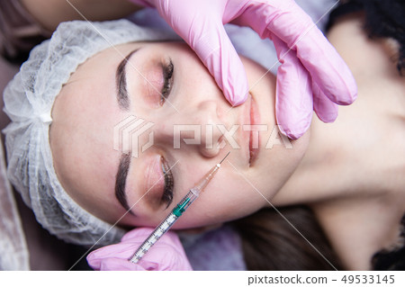 The doctor cosmetologist makes the Rejuvenating facial injections procedure for tightening and 49533145