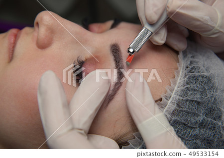 Permanent Makeup For Eyebrows. Microblading brow. Beautician Doing Eyebrow Tattooing For Female Face Permanent Makeup For Eyebrows. Microblading brow. Beautician Doing Eyebrow Tattooing For Female Face 49533154