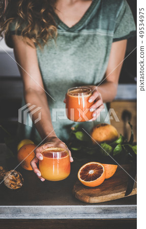 Woman holding glasses with fresh blood orange 49534975