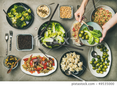 Healthy vegan dishes and woman hand adding Healthy vegan dishes and woman hand adding 49535000