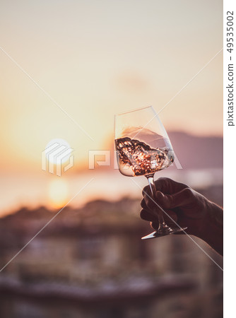 Man's hand holding rose wine with sea at Man's hand holding rose wine with sea at 49535002