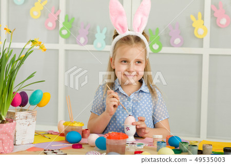 little child girl with Easter bunny ears painting Easter eggs at home. little child girl with Easter bunny ears painting Easter eggs at home. 49535003