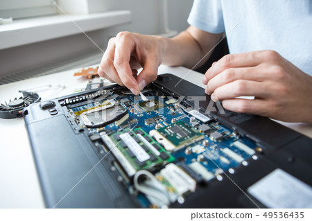 Man examines laptop PC clean thermal paste Man examines laptop PC clean thermal paste 49536435