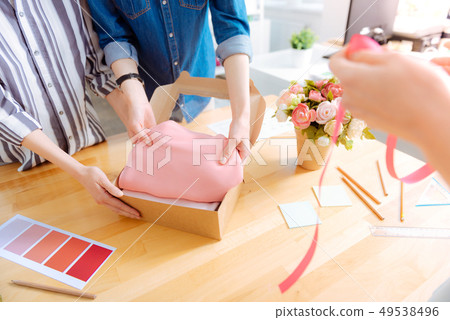 Competent tailor putting pink cloth into box 49538496