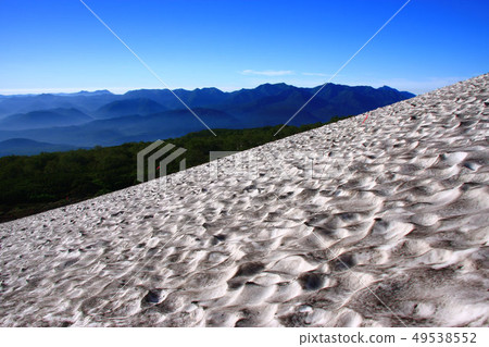 Snowy mountain in the summer and mountain range of eastern heavy snow seen from Daisetsuzan Akadake mountain trail Snowy mountain in the summer and mountain range of eastern heavy snow seen from Daisetsuzan Akadake mountain trail 49538552