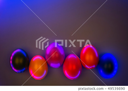 Creative photo of colorful eggs in neon lights on grey background. 49539890