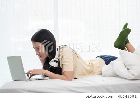 Smiling asia woman using a laptop while lying on 49543591