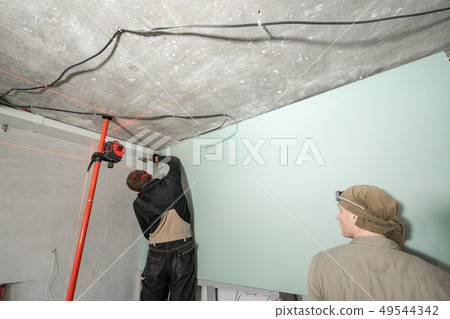 drywall installation, wall alignment. Laser measurement during renovation. Construction tools and 49544342