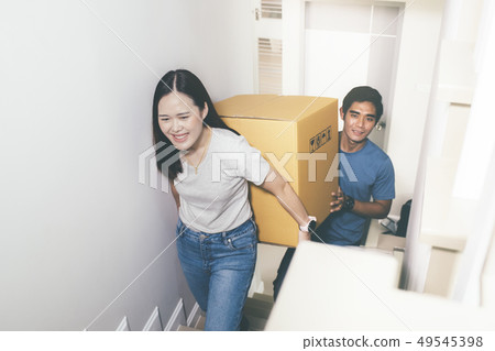 Couple carrying heavy moving boxes together. Couple carrying heavy moving boxes together. 49545398