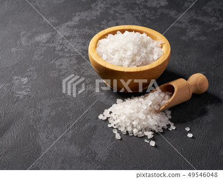 White salt in wooden bowl on black background White salt in wooden bowl on black background 49546048