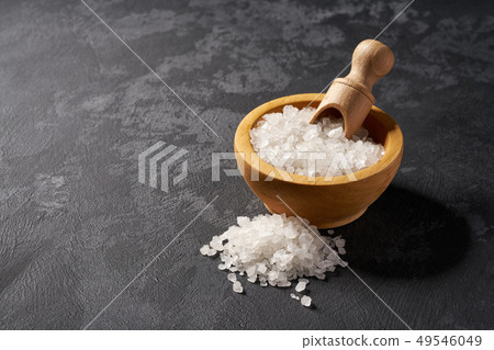 White salt in wooden bowl on black background White salt in wooden bowl on black background 49546049