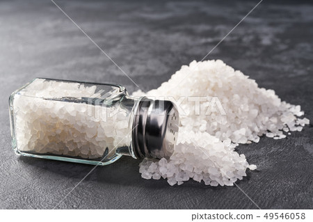 Pile of salt and salt shaker on black stone Pile of salt and salt shaker on black stone 49546058
