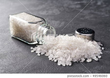 Pile of salt and salt shaker on black stone Pile of salt and salt shaker on black stone 49546060