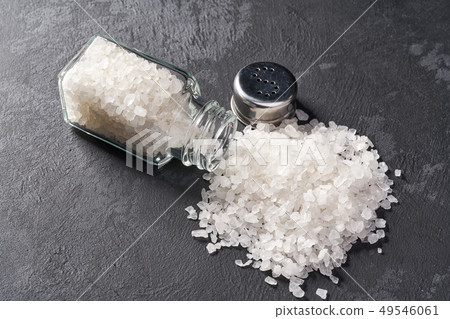 Salt shaker with spilled salt on black stone Salt shaker with spilled salt on black stone 49546061