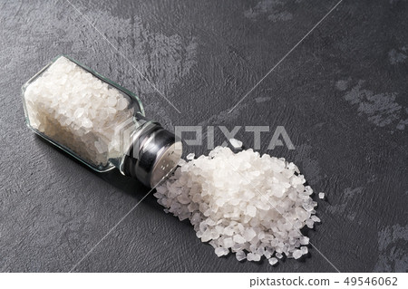 Salt shaker with spilled salt on black stone Salt shaker with spilled salt on black stone 49546062