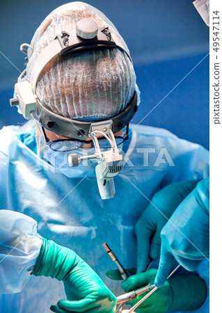 Close up portrait of female surgeon doctor wearing protective mask and hat during the operation 49547114