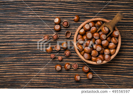 Hazelnut with peeled hazelnuts on a brown wooden Hazelnut with peeled hazelnuts on a brown wooden 49556597
