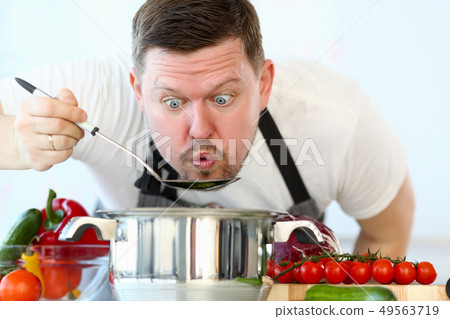 Male cook tries hot soup from pan Male cook tries hot soup from pan 49563719