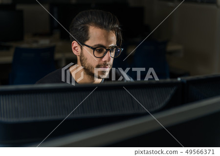 View over a screen of the face of a young computer science student working with the computer. 49566371