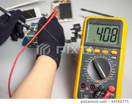 Technician repairing broken smartphone on desk Technician repairing broken smartphone on desk 49568775