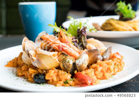 美味的平底鍋炒海鮮飯。頂面茄子,鮭魚,煎餅,海鮮。 美味的平底鍋炒海鮮飯。頂面茄子,鮭魚,煎餅,海鮮。 49568823