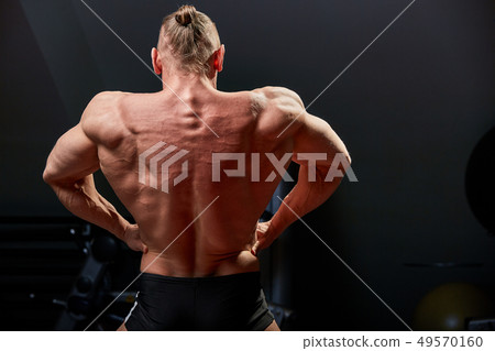 Athletic man posing. Photo of man with perfect physique on black background. Back view. Strength and Athletic man posing. Photo of man with perfect physique on black background. Back view. Strength and 49570160
