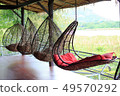 rattan oval hanging chair with red pillow in tropi 49570292