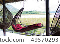 rattan oval hanging chair with red pillow in tropi 49570293