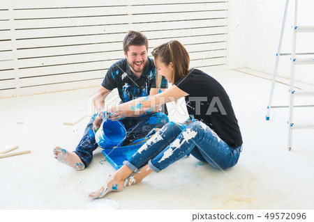 Renovation, redecoration and interiors concept - Young couple sitting on the white floor and pour 49572096