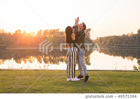 Romantic, social dance and people concept - young couple dancing a tango or bachata near the lake Romantic, social dance and people concept - young couple dancing a tango or bachata near the lake 49572384