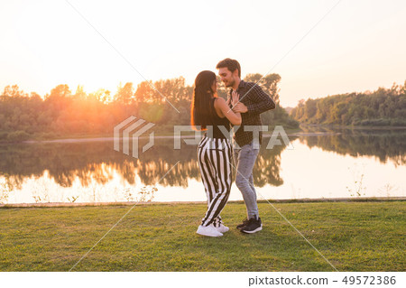 Romantic, social dance and people concept - young couple dancing a tango or bachata near the lake Romantic, social dance and people concept - young couple dancing a tango or bachata near the lake 49572386
