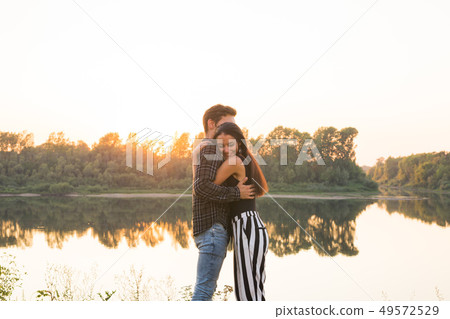 Romantic and people concept - young couple hugging together near the river or lake and enjoying 49572529