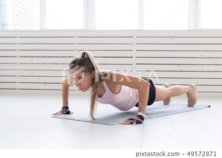 Healthy lifestyle, sport, people concept - a young woman is doing fitness in the gym or home. She is Healthy lifestyle, sport, people concept - a young woman is doing fitness in the gym or home. She is 49572871