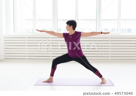 Yoga, people concept - a middle-aged woman doing a yoga and try to do a asana Yoga, people concept - a middle-aged woman doing a yoga and try to do a asana 49573040