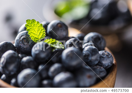 Wooden bowl full of fresh blueberries with herbs Wooden bowl full of fresh blueberries with herbs 49573700
