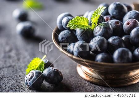 Vintage bowl full of fresh blueberries with herbs. Vintage bowl full of fresh blueberries with herbs. 49573711
