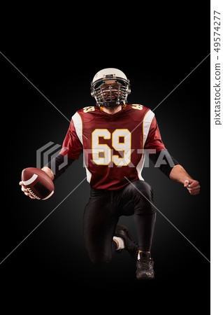 Portrait of American football player holding a ball with both his hands 49574277