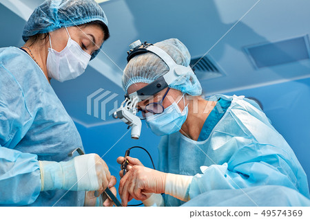 Portrait of professional surgeons during surgery on a blue background. Concept surgery, medicine Portrait of professional surgeons during surgery on a blue background. Concept surgery, medicine 49574369